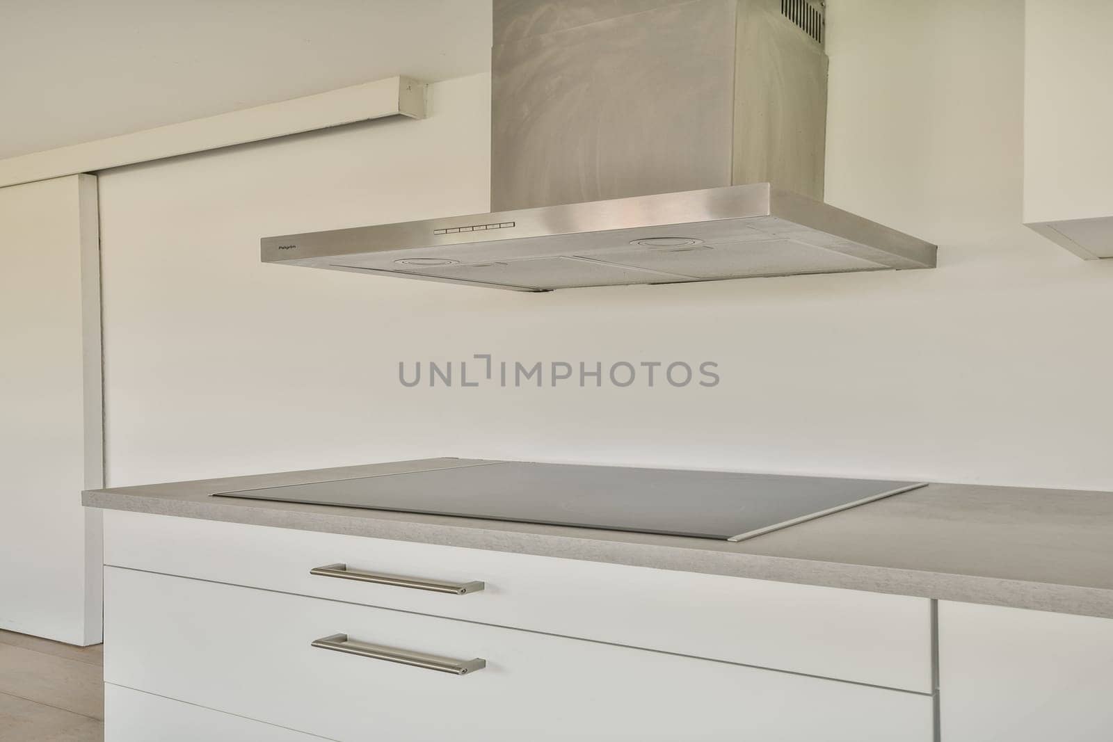 A minimalist kitchen featuring a sleek countertop, a stylish range hood, and clean lines, ideal for contemporary living.