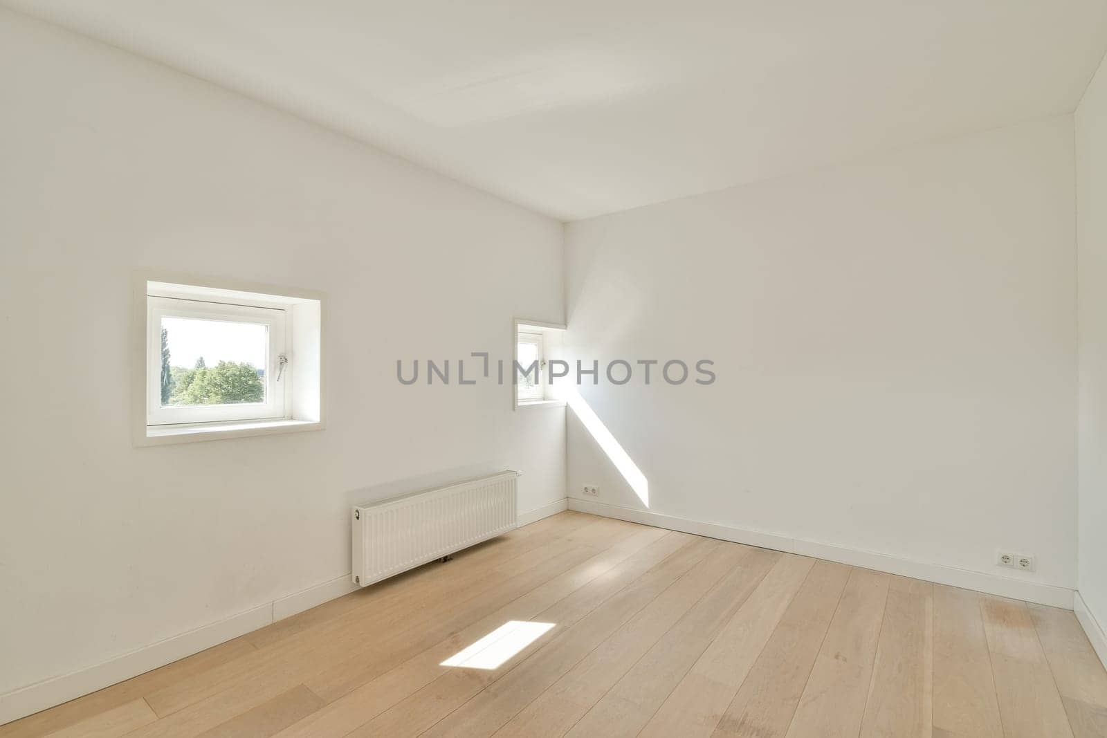 A spacious, bright empty room featuring large windows and wooden flooring, showcasing a minimalist design aesthetic. Perfect for showcasing interior concepts.