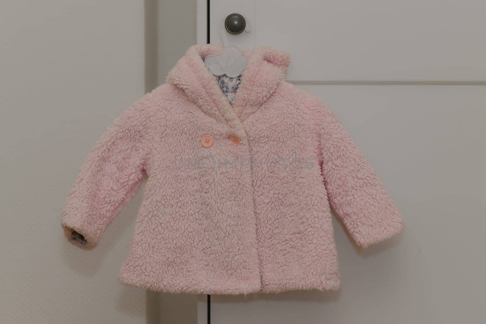 Pink winter artificial fur jacket hanging on a hanger on a white background