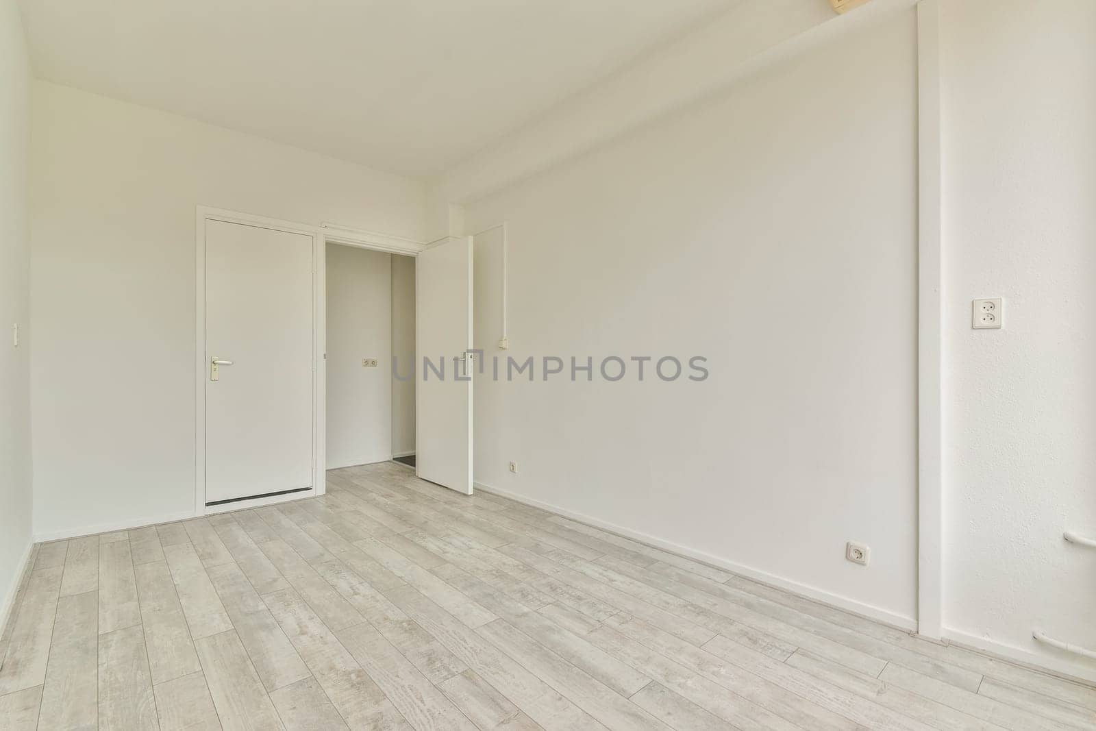 A spacious, minimalist interior showcasing an empty room with light-colored walls and wooden floors, ideal for showcasing modern design concepts.