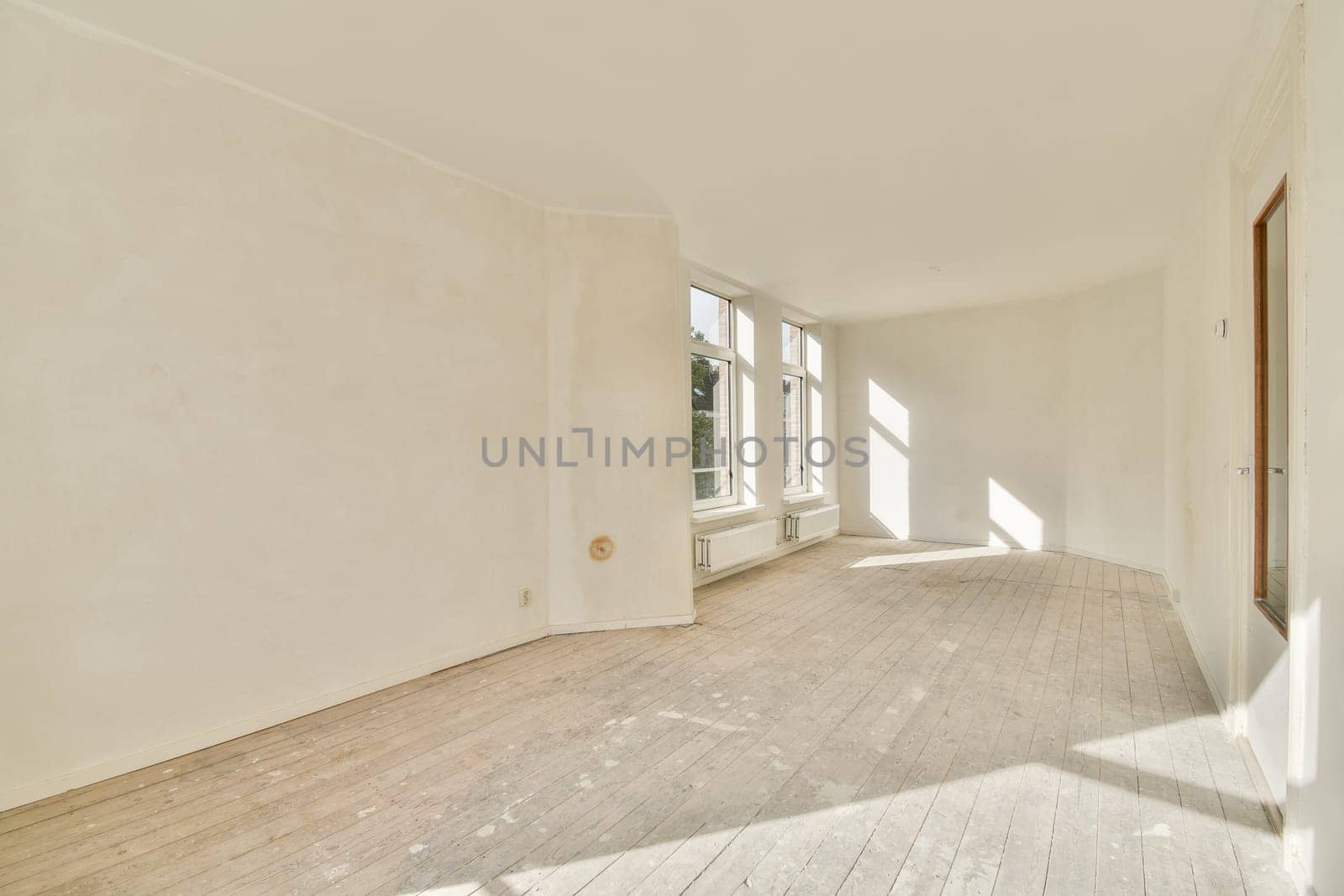 A spacious, minimalist room filled with natural light, showcasing clean lines and a serene atmosphere. Features large windows and wooden flooring for added warmth.
