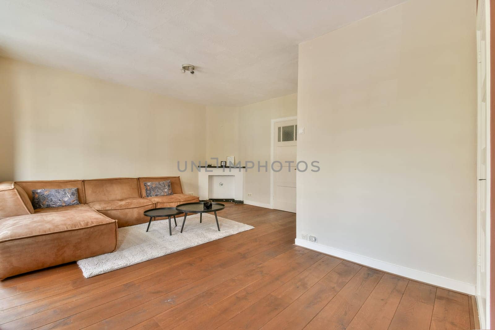 A spacious and stylish living room featuring a comfortable sofa, minimalist decor, and a warm wooden floor, perfect for relaxation and socializing.
