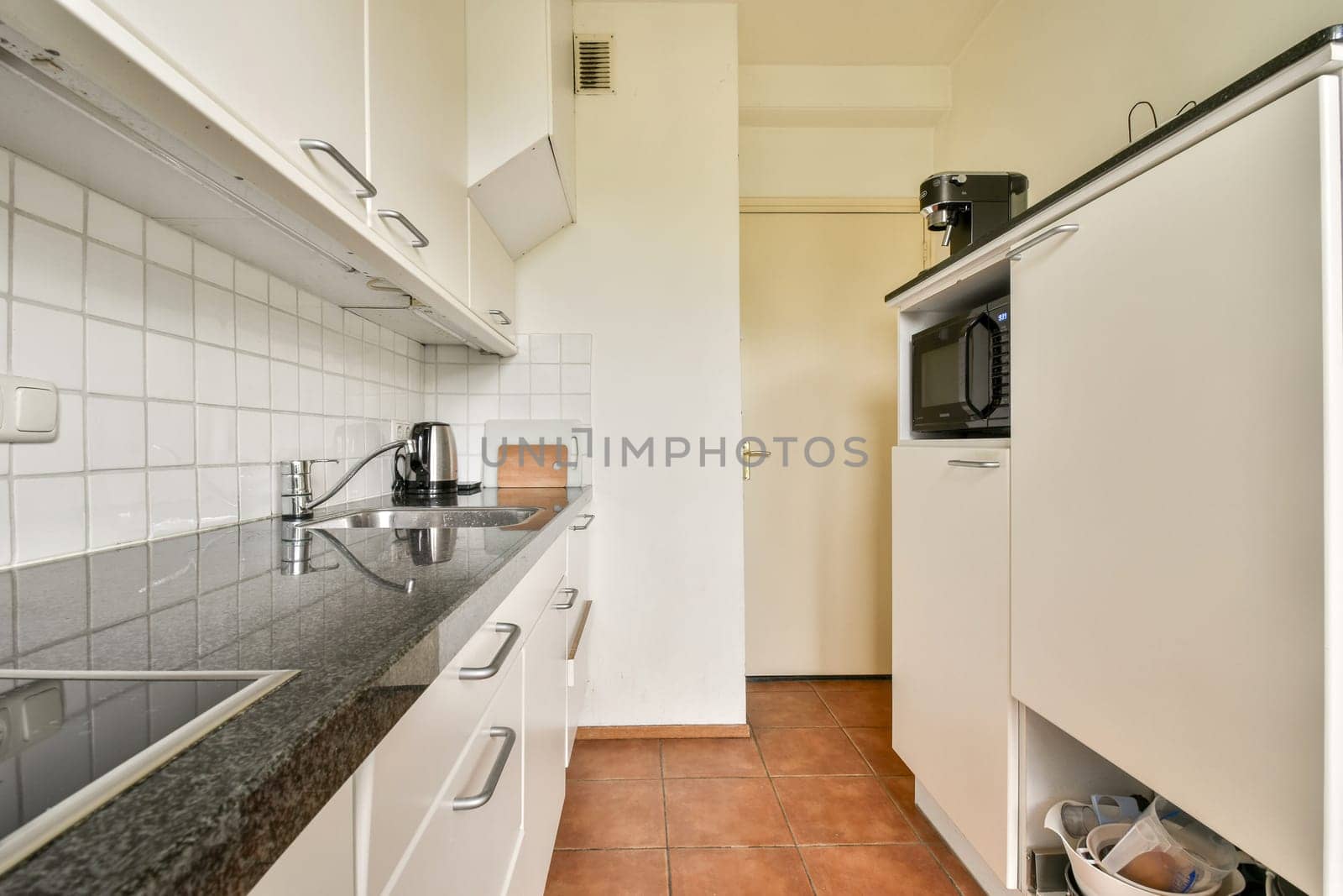 A sleek, modern kitchen featuring minimalistic cabinetry, granite countertops, and a well-organized layout creating an efficient cooking space.