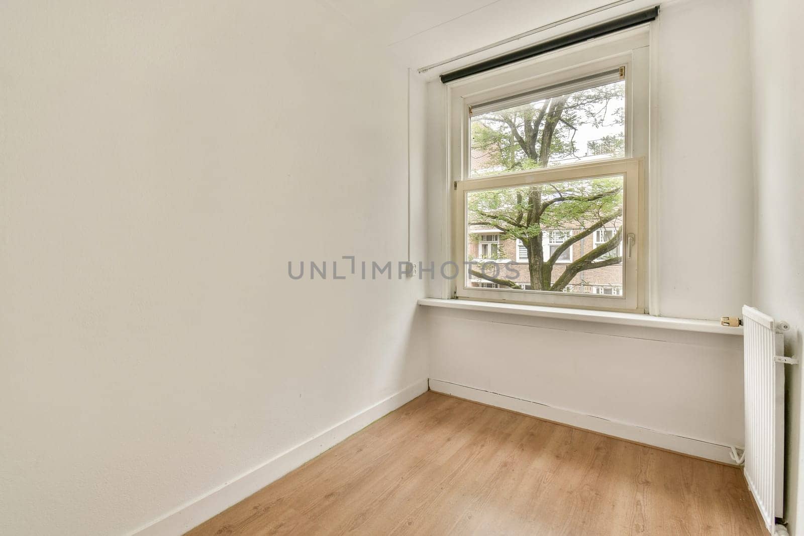 A spacious, well-lit room featuring a large window that invites natural light. The simple decor emphasizes minimalism and tranquility.