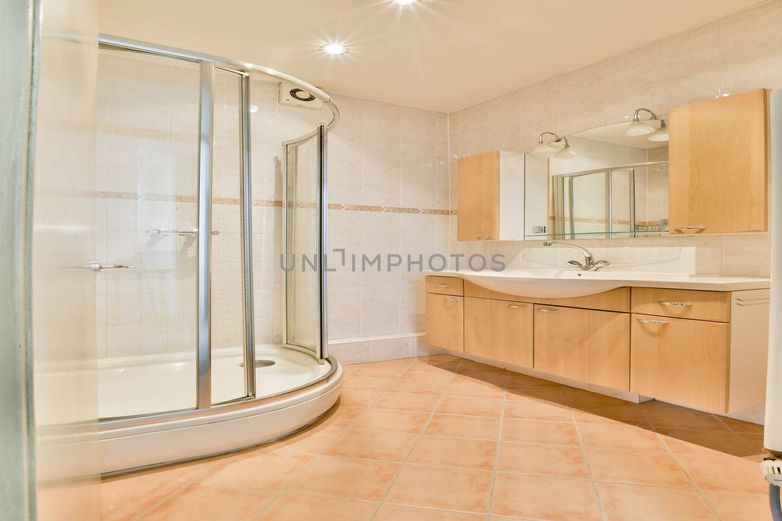 A stylish bathroom featuring a glass shower, wooden cabinets, and modern fixtures. The design emphasizes clean lines and a spacious layout for comfort.