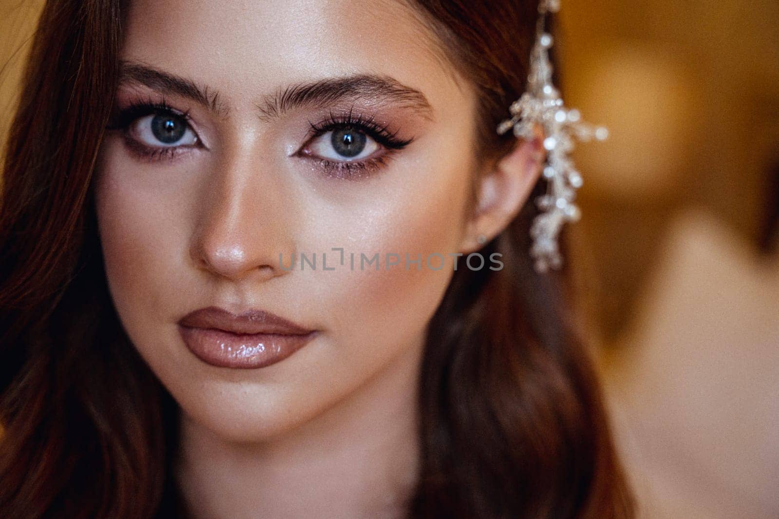 close-up, portrait of a young brunette bride in a white dress with a corset. Long hair is styled in a wave, white decoration of small pearls in her hair on the side. Portrait of the bride, wedding makeup and hairstyle.