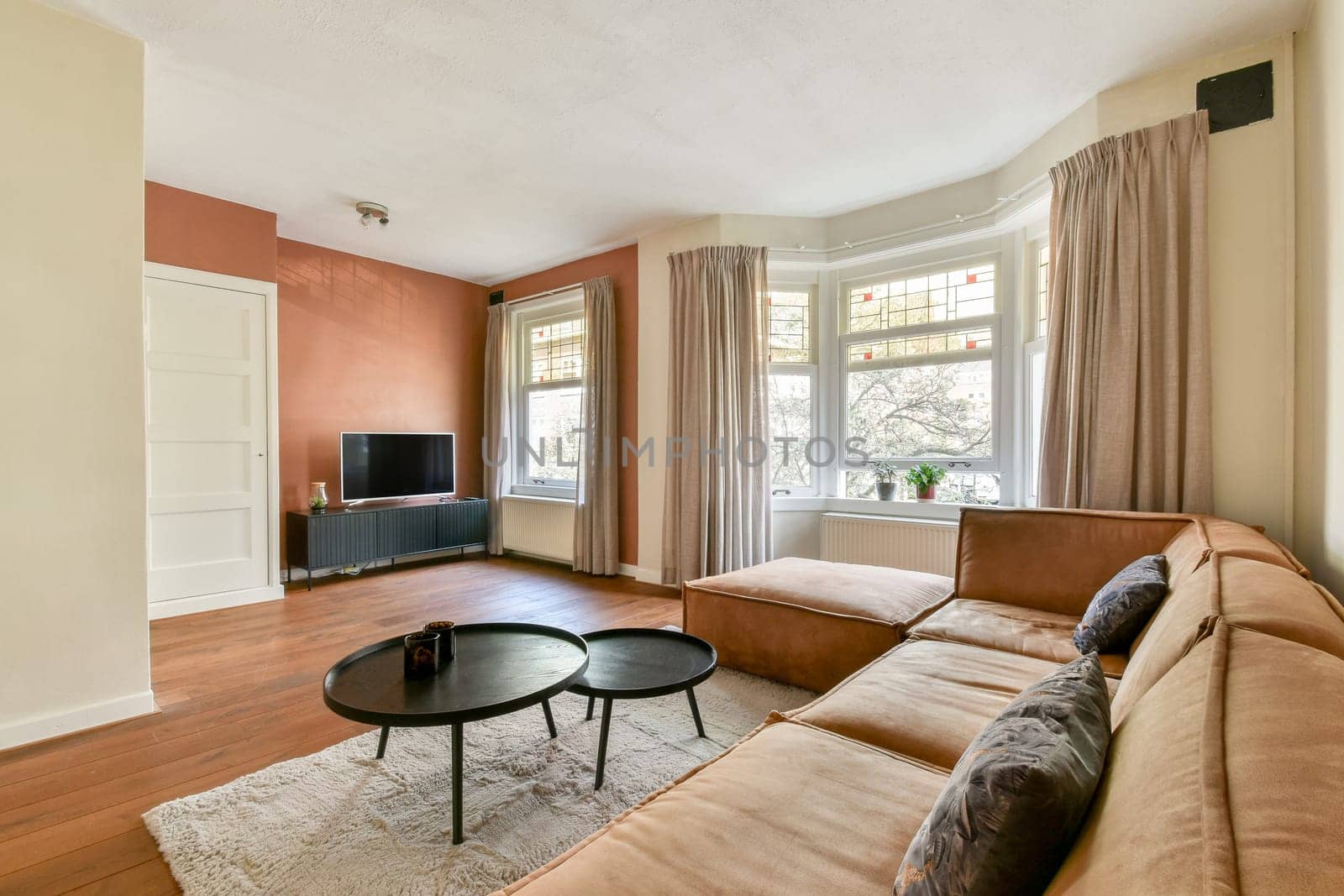A stylish and cozy modern living room featuring a comfortable couch, a coffee table, and large windows that brighten the space with natural light.