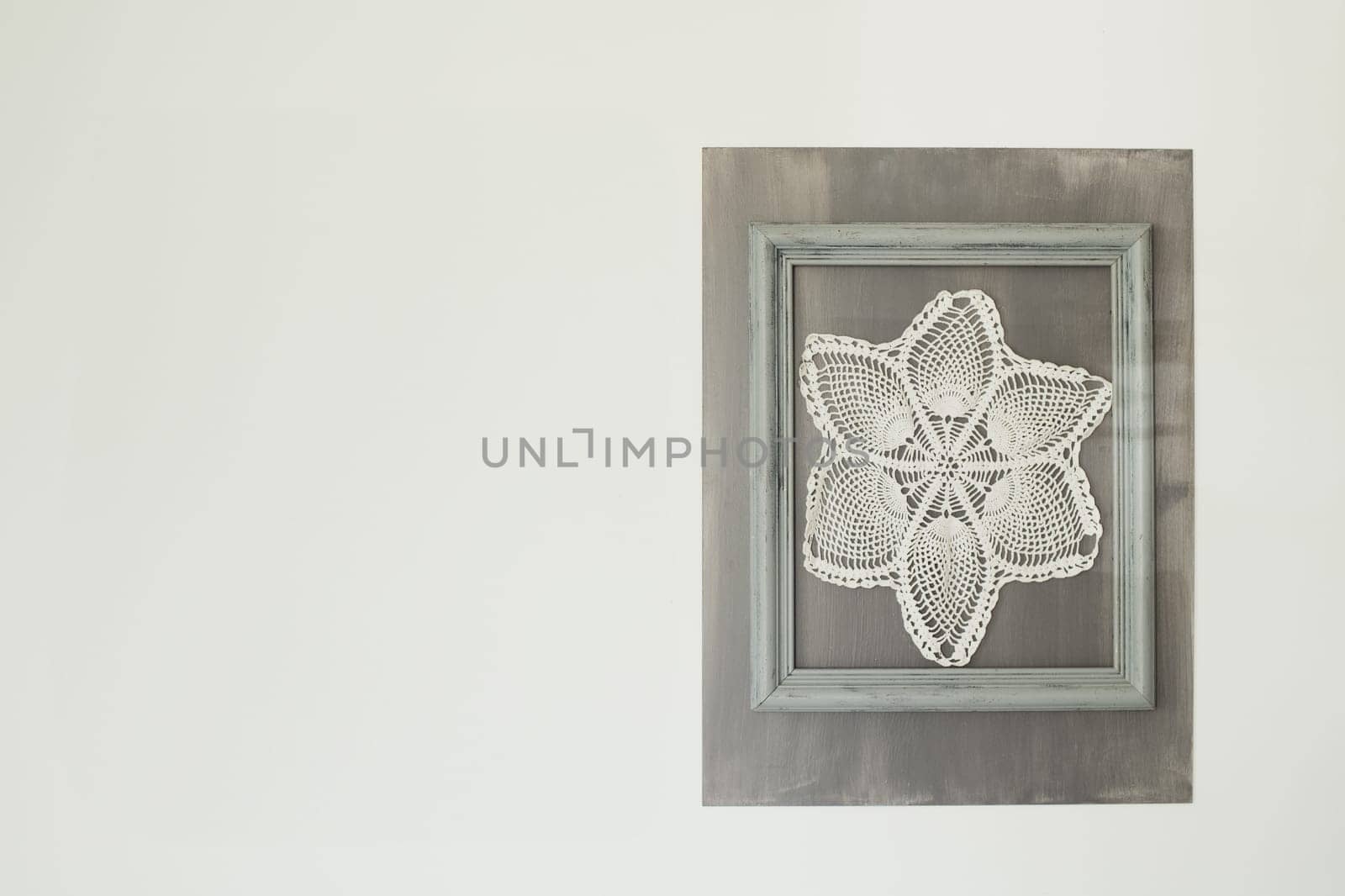 Crocheted napkins hang in a frame on the wall Village style
