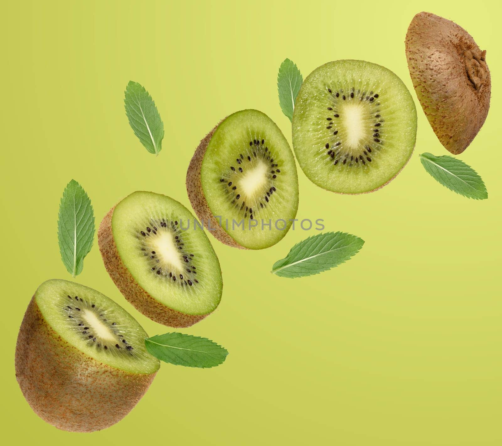Sliced ​​ripe kiwi fruit and green mint leaves levitate on light green background