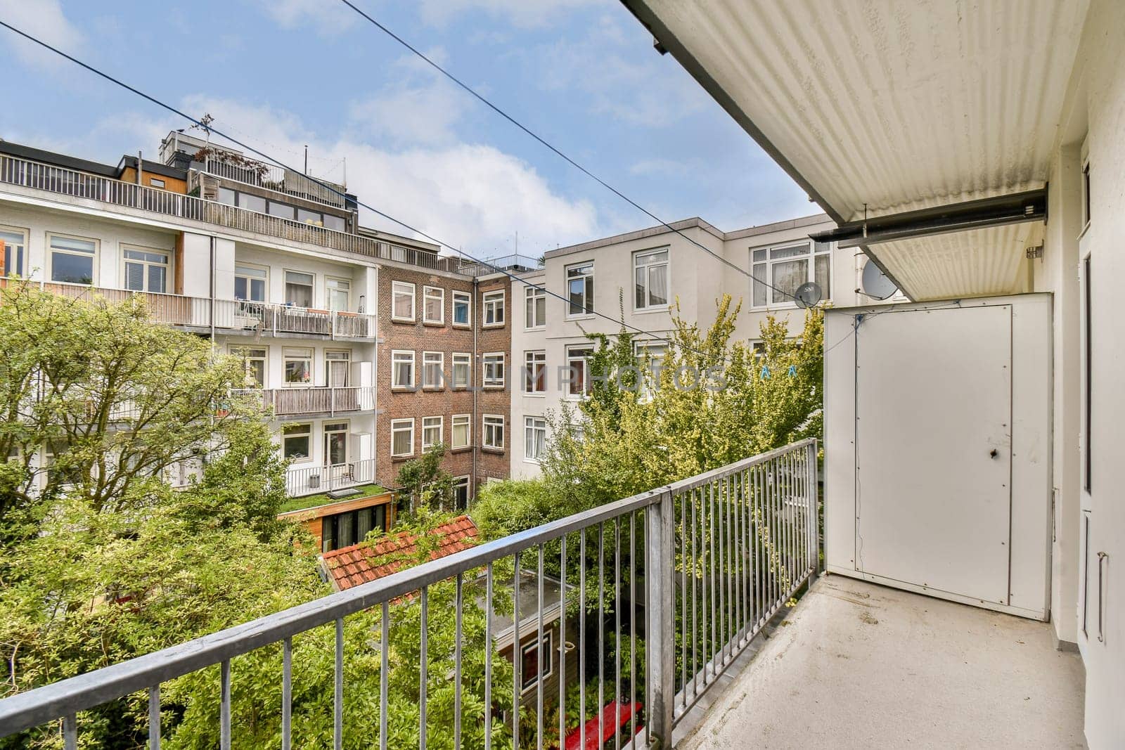 A serene balcony view capturing an urban scene with residential buildings surrounded by greenery. Ideal for exploring city life and architecture.