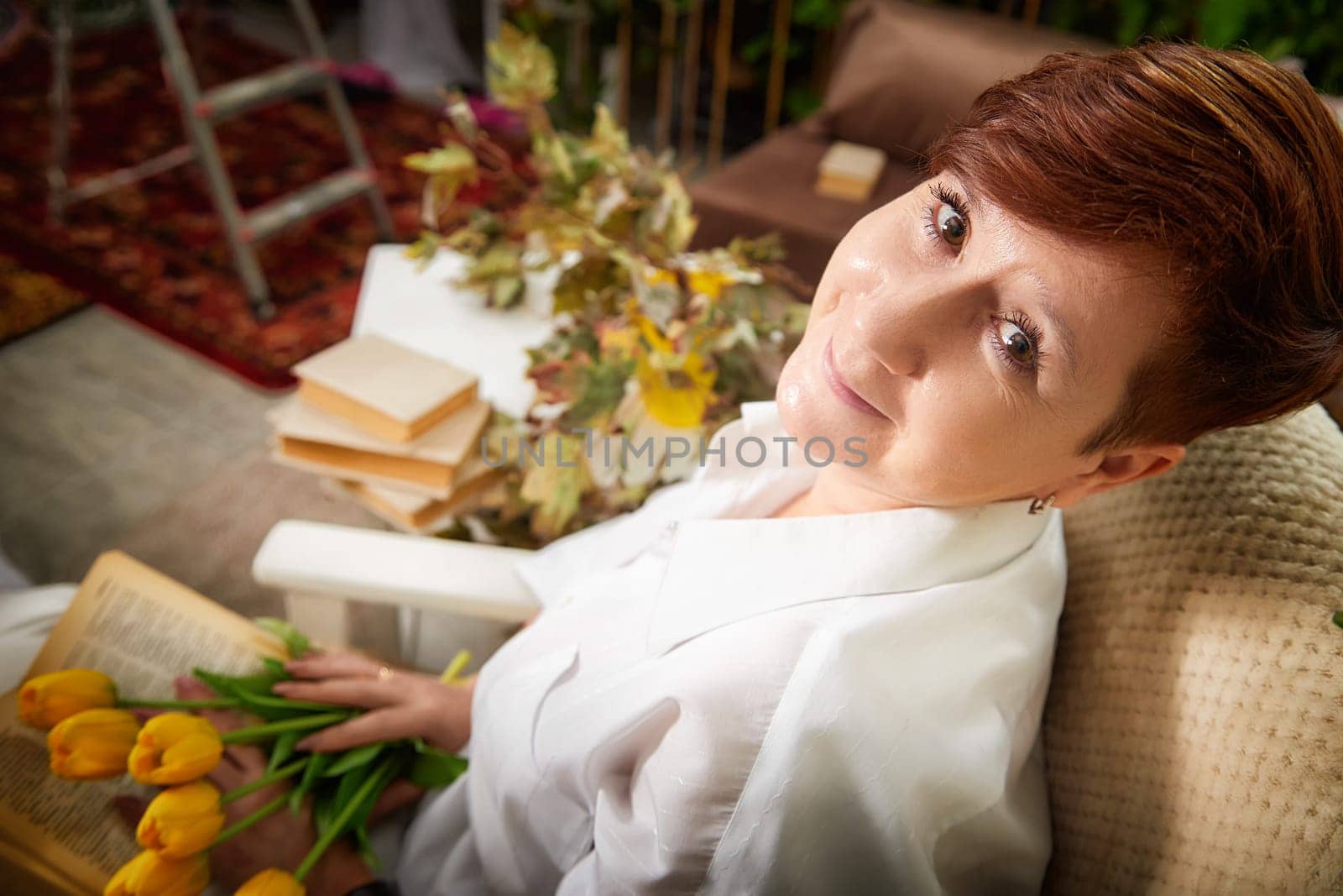 A mature woman holds a tulip bouquet, celebrating Women's Day in her cozy space.