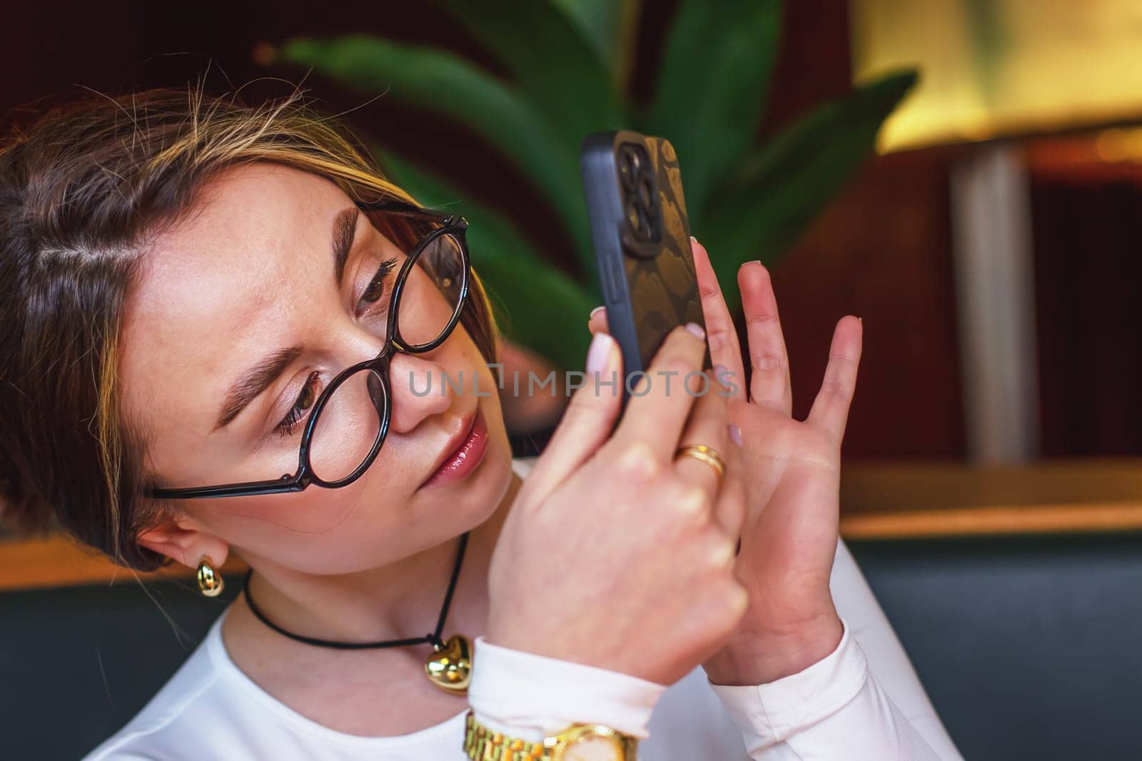 Beautiful young woman in glasses taking pictures on her phone. High quality photo