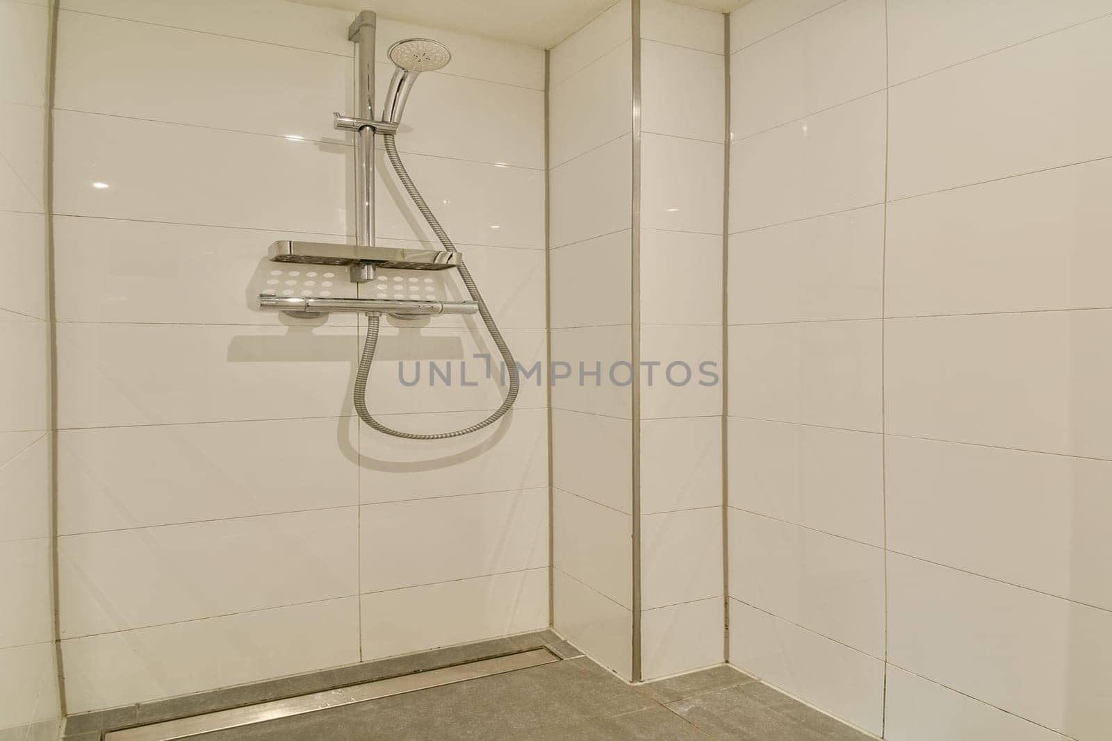 A sleek and minimalist shower stall featuring white tiled walls and a contemporary showerhead. The design emphasizes simplicity and cleanliness.