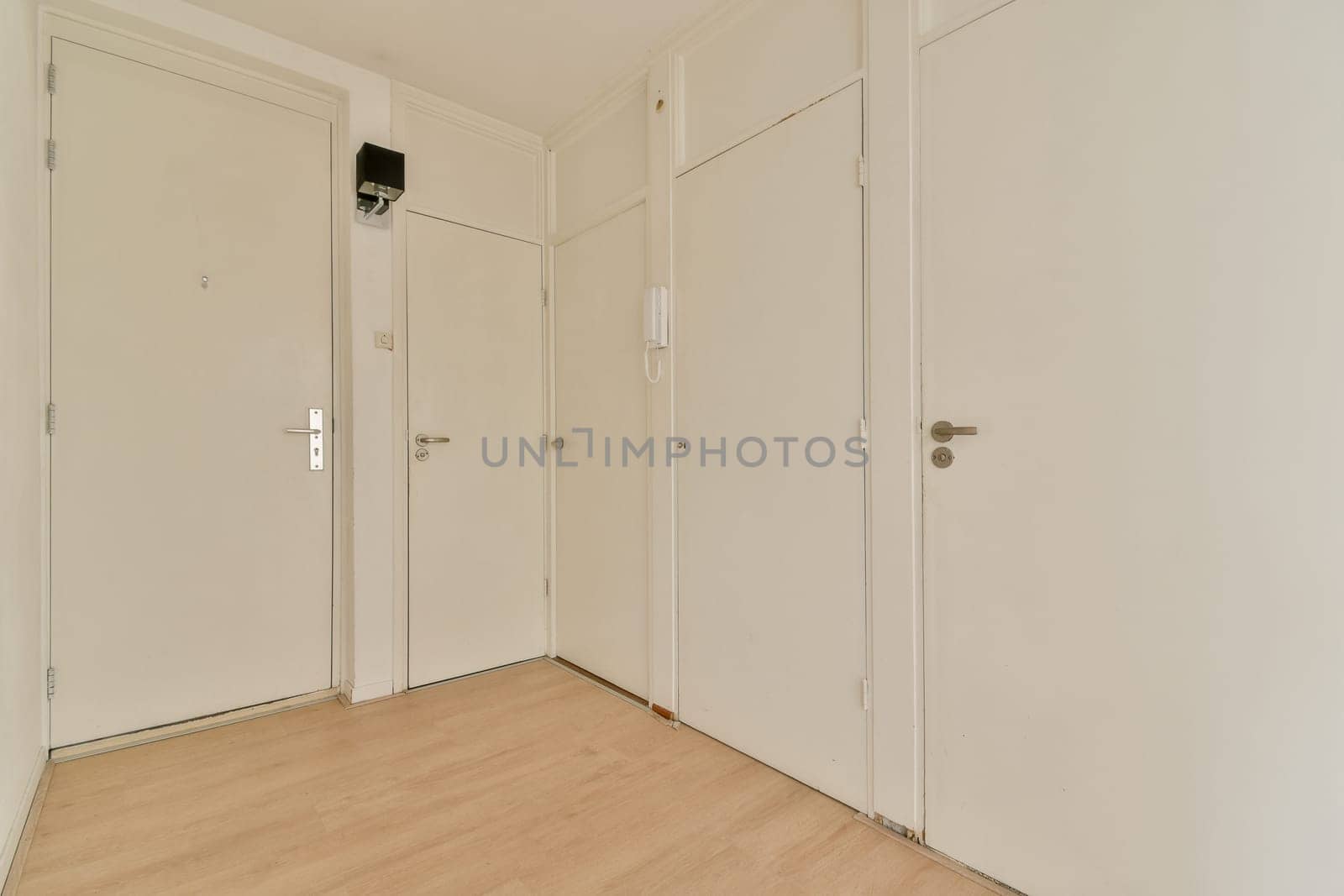 A bright and minimalist hallway featuring white walls and wooden flooring, offering a modern and spacious feel. Ideal for showcasing minimalist design.