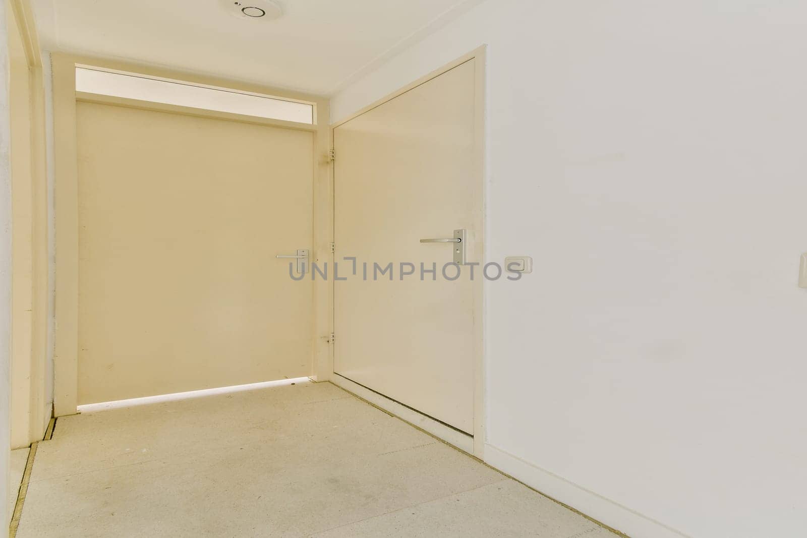 A clean and simple design showcases a modern interior doorway, emphasizing minimalism with neutral colors and soft lighting in this spacious hallway.