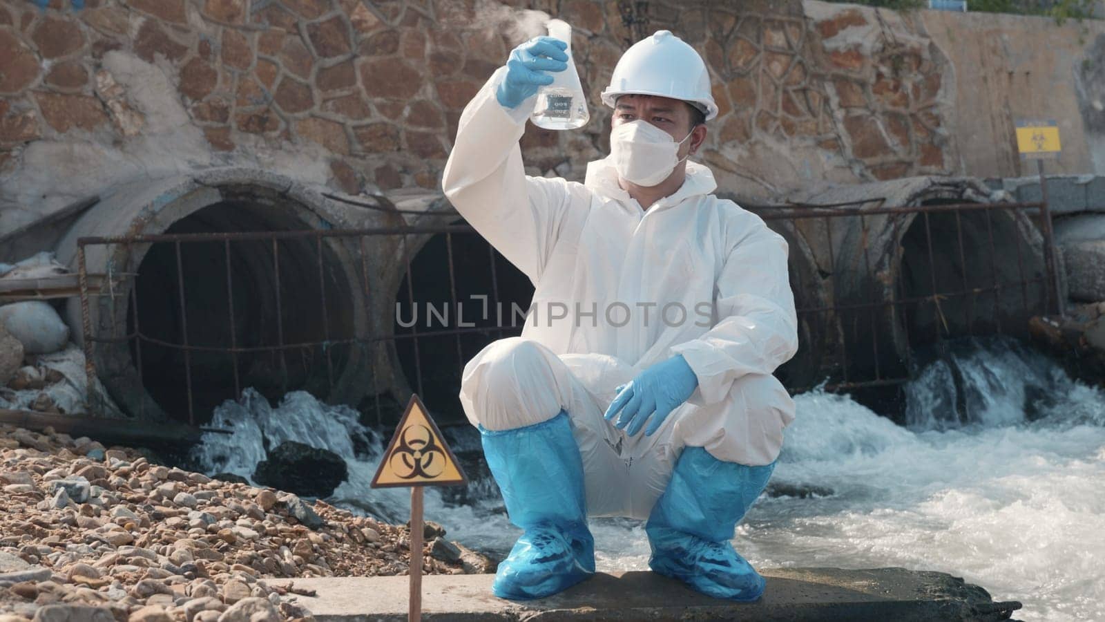 Ecologist sampling water toxic chemicals from river with test tube glass and have white smoke, Biologist wear protective suit and mask collects sample waste water from industrial, problem environment