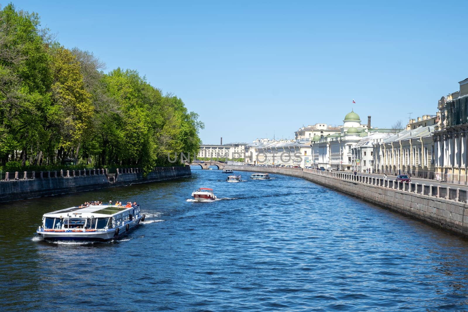 Saint-Petersburg, Russia - 05.21.24. River Fontanka scene with several boats cruising along a scenic waterway flanked by trees of Summer garden and historic architecture.