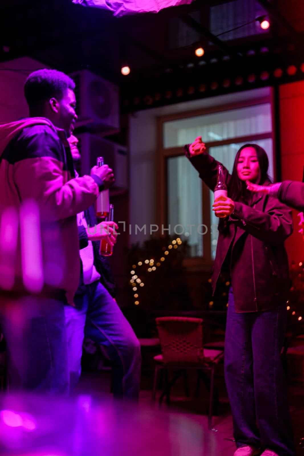 A group of friends celebrates a night out with drinks in hand while dancing and enjoying music in a colorful and lively venue, illuminated with enchanting lights.
