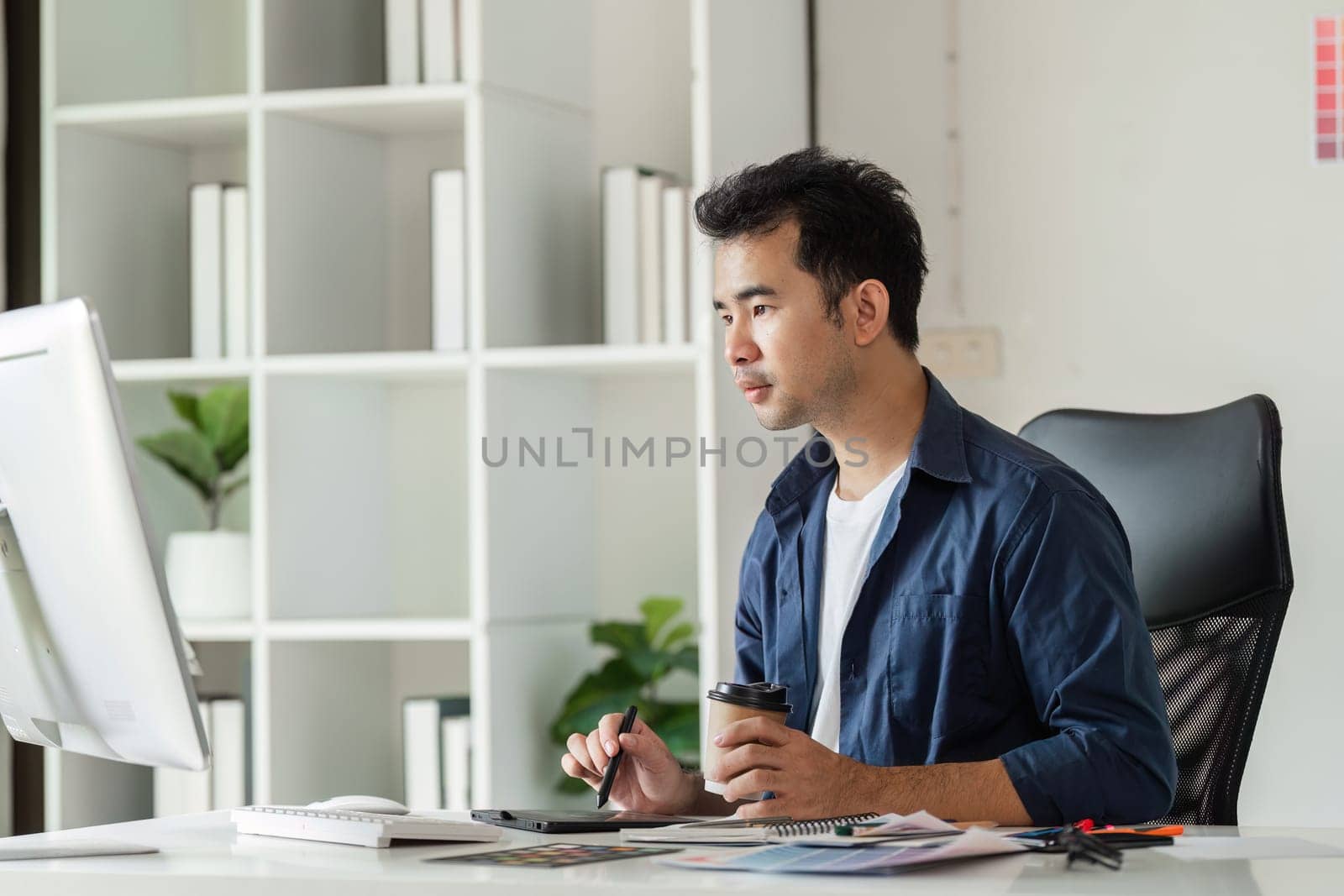 A graphic designer deeply engaged in work at a modern design studio, utilizing digital tools and a creative workspace.