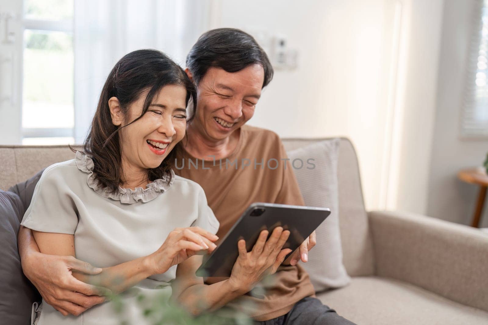 A retired couple relaxes in their living room, enjoying a comfortable and peaceful lifestyle with modern decor and natural light.