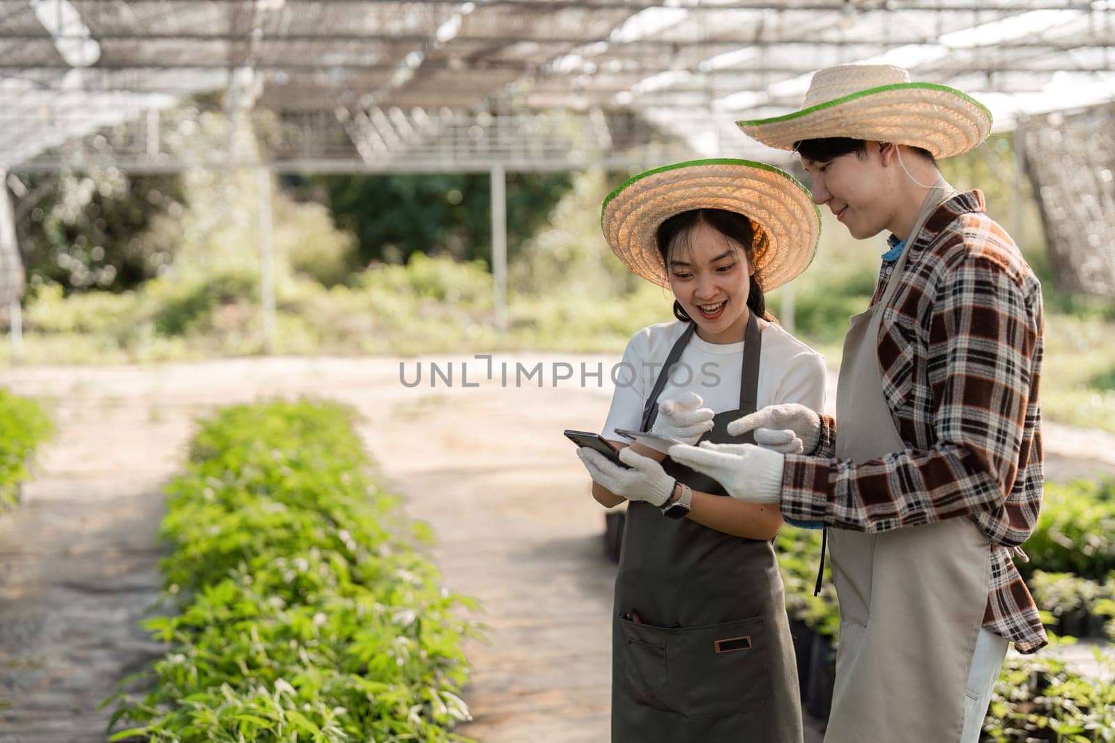 A couple utilizes modern technology to grow an herbal garden, blending innovation with nature in a greenhouse environment.
