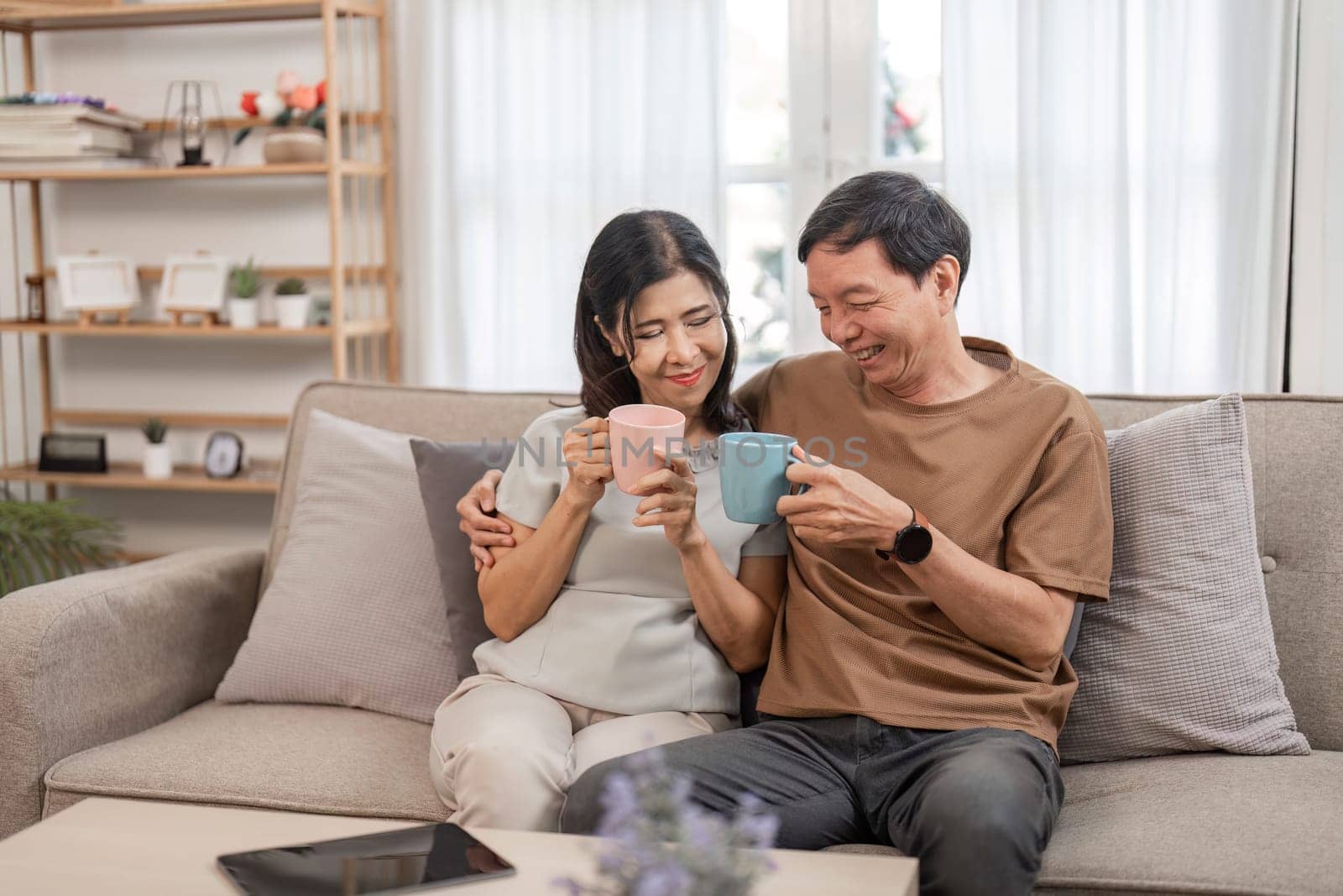 Senior couple working together on financial planning, using laptops and documents, showcasing teamwork and support in a cozy home setting.