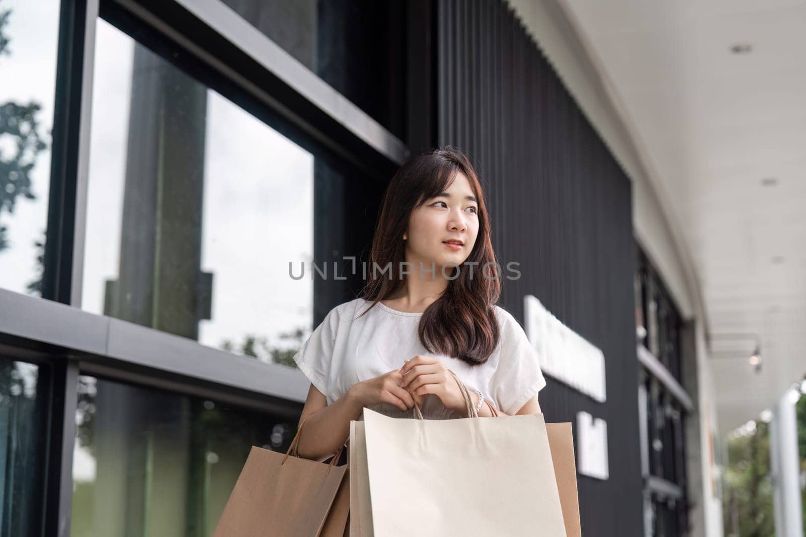 A young woman happily carries shopping bags after a successful Black Friday shopping spree in a contemporary urban environment.