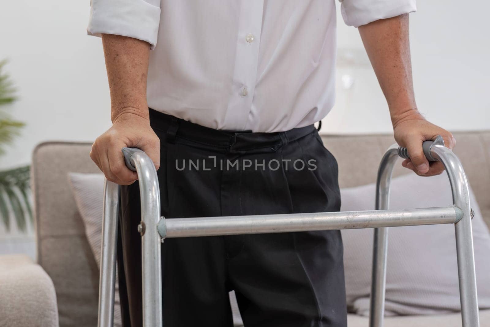 An elderly man uses a cane for support while walking indoors, highlighting independence and mobility in senior life.