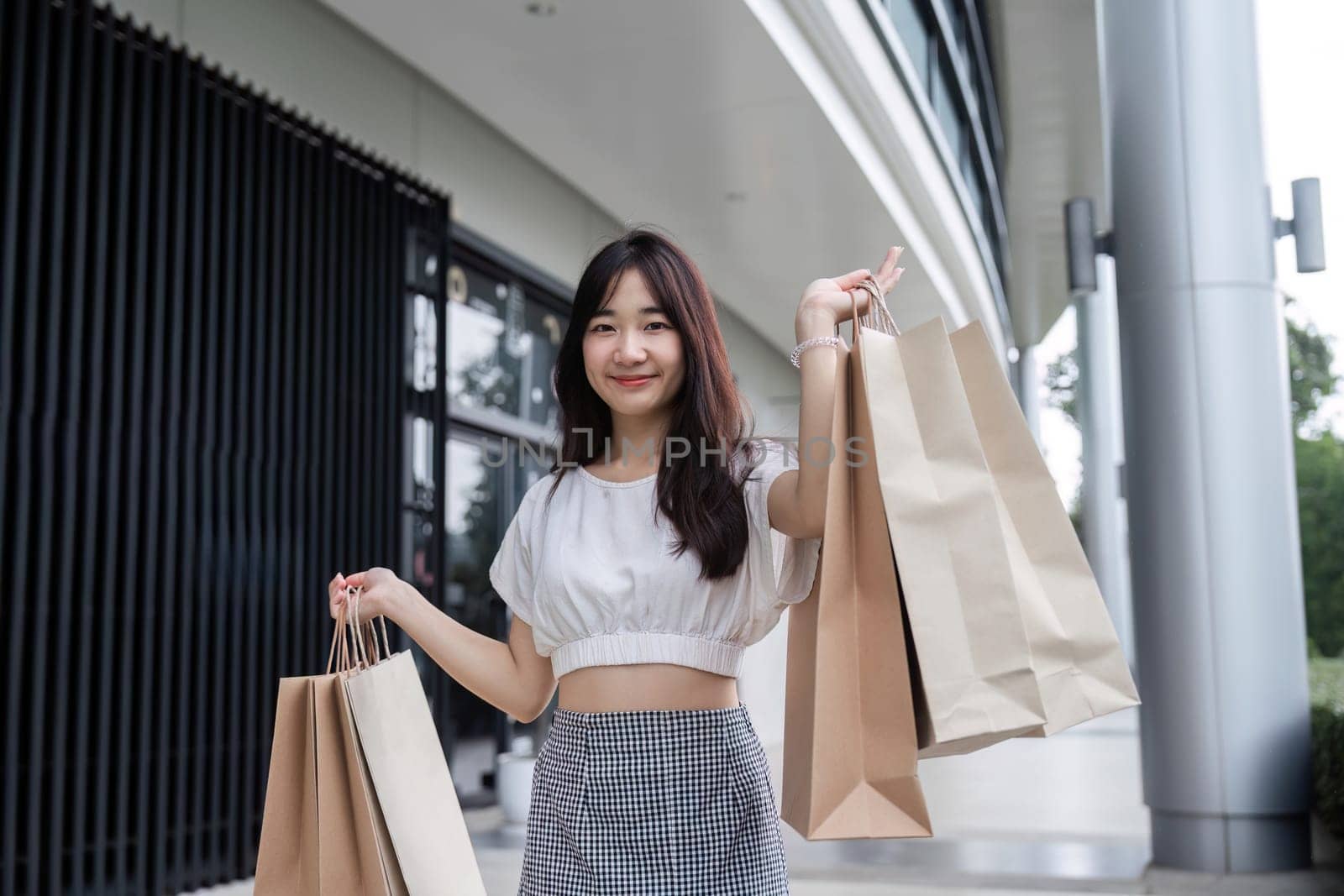 A young woman happily carries shopping bags after a successful Black Friday shopping spree in a contemporary urban environment.