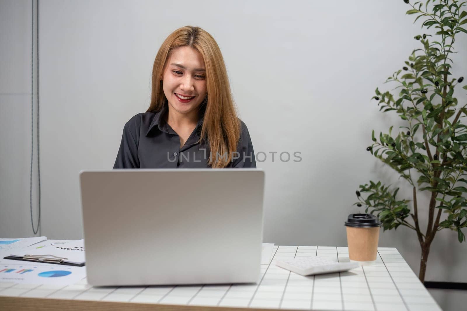 Professional businesswoman reviewing graphs on a laptop, focusing on data analysis in a contemporary office environment.