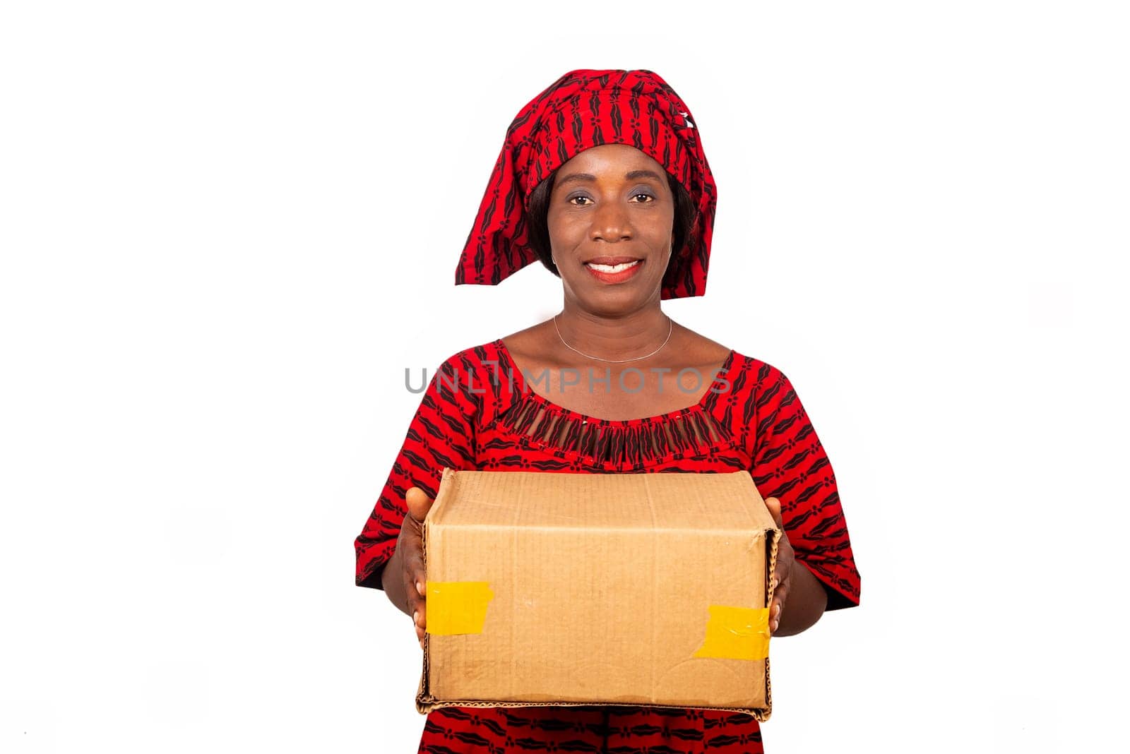 beautiful african adult woman dressed in red loincloth standing holding a cardboard box smiling. isolated on white background