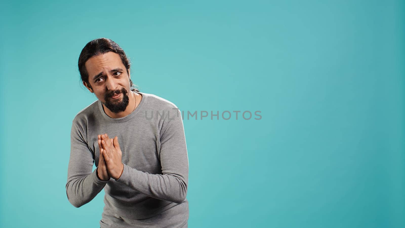 Man putting hands together in apology gesture, asking for forgiveness. Apologetic person doing sorry gesturing, asking for pardon, isolated over studio background, camera B