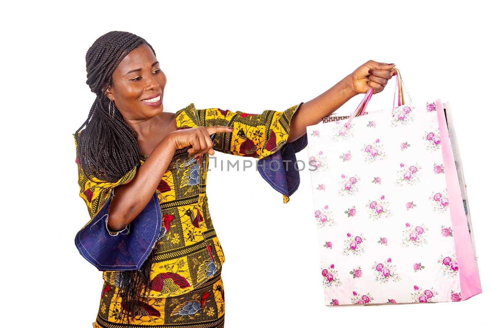 beautiful african mature woman standing pointing at some shopping bag isolated on white background