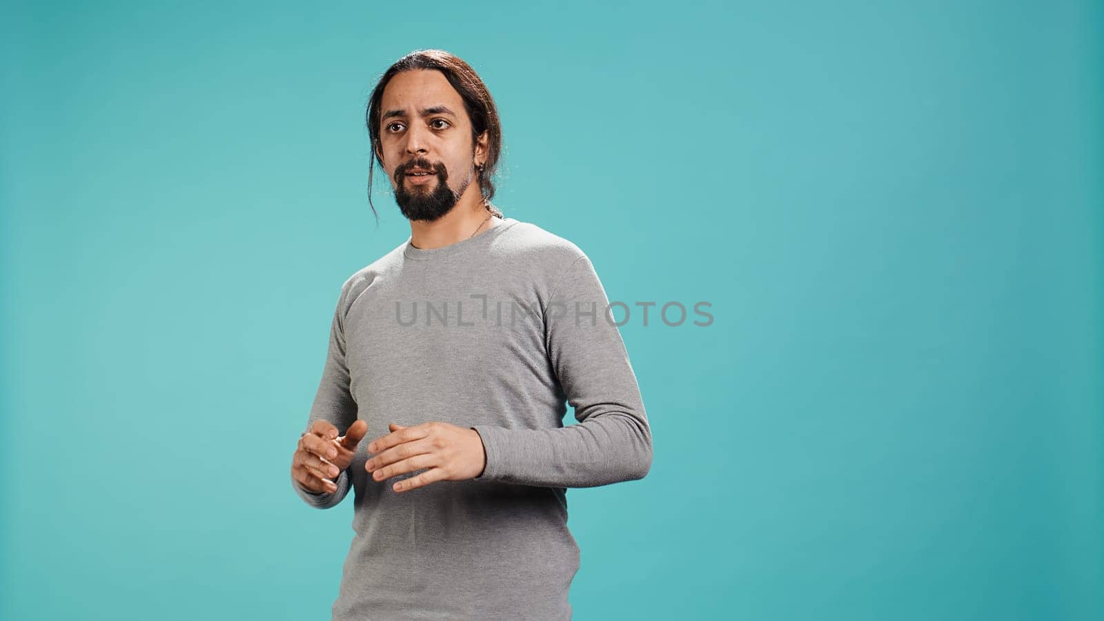 Portrait of frightened man covering his face with hands, standing isolated against studio background. Scared person with fearful facial expression suffering shock, feeling distraught, camera B