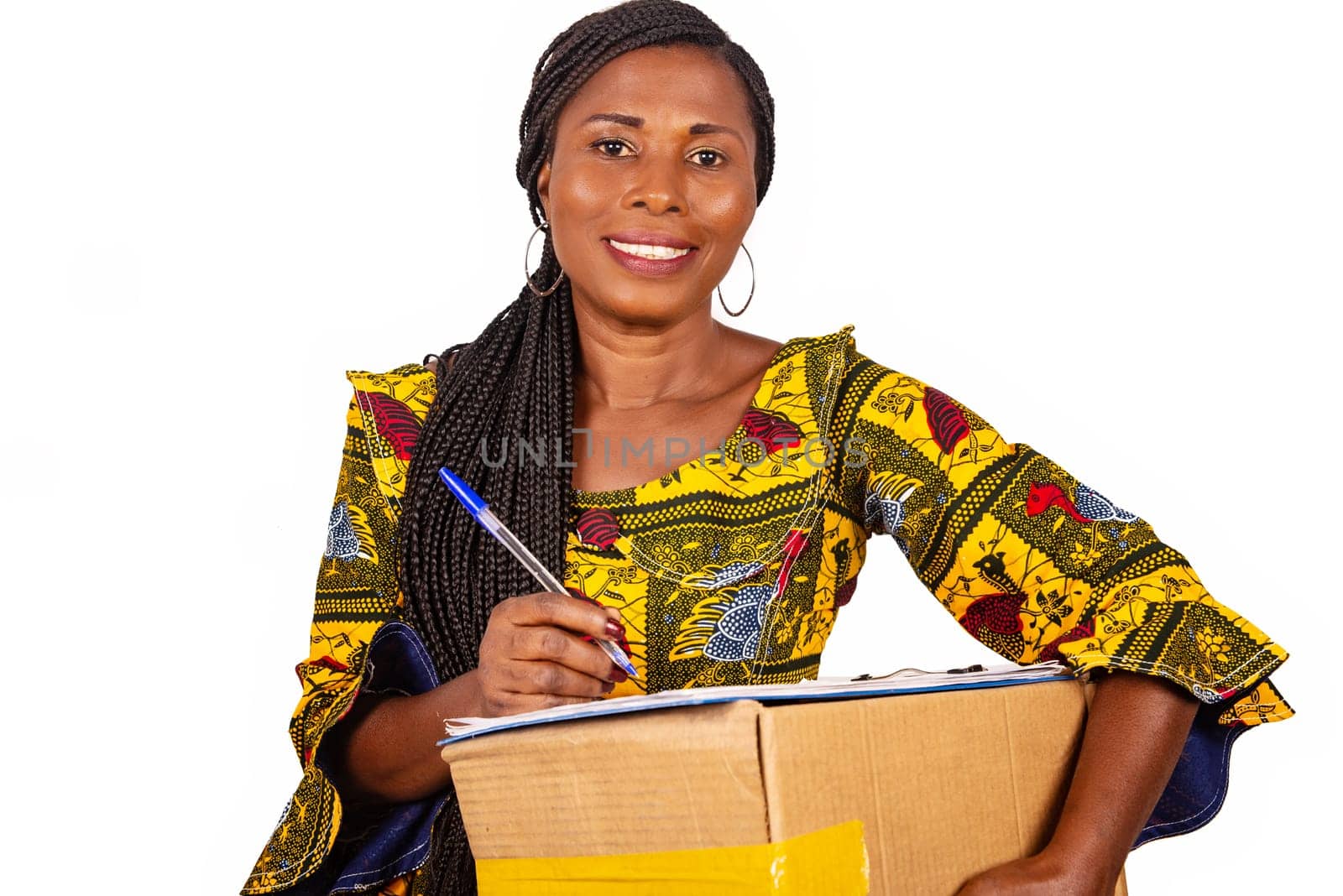 beautiful african woman standing in traditional outfit on white background smiling ready to sign a document after receiving a package.