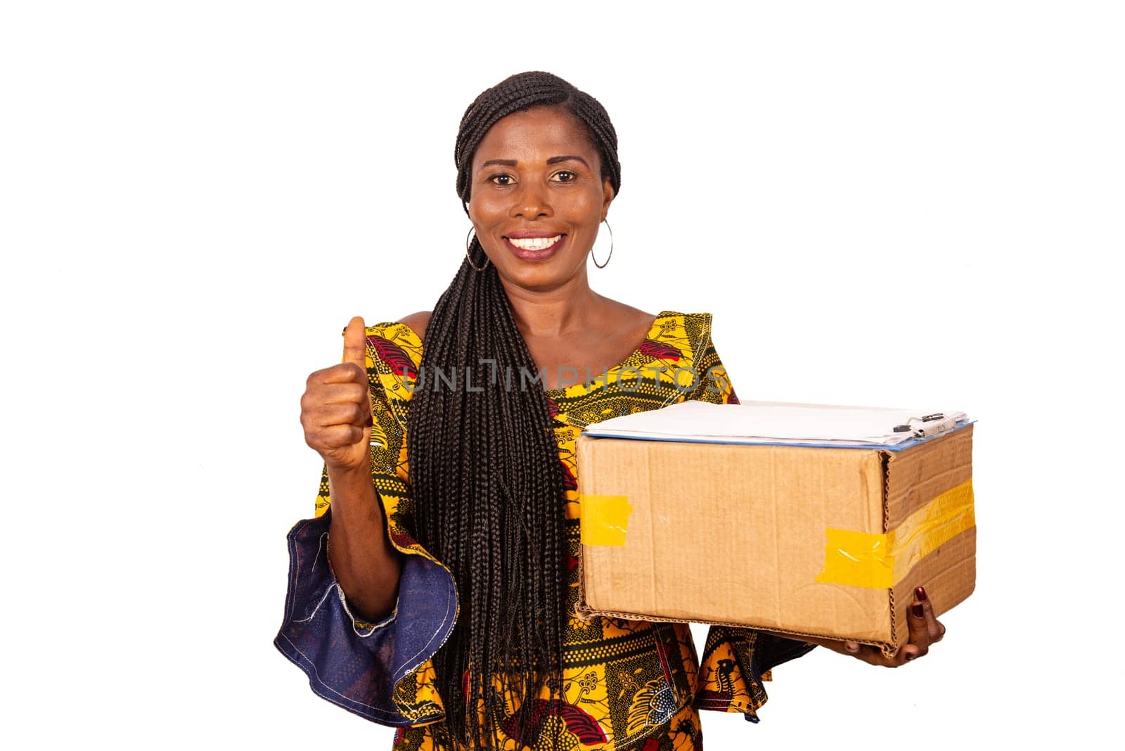 beautiful african woman in traditional clothes standing on white background looking at camera smiling and carrying a delivery package.