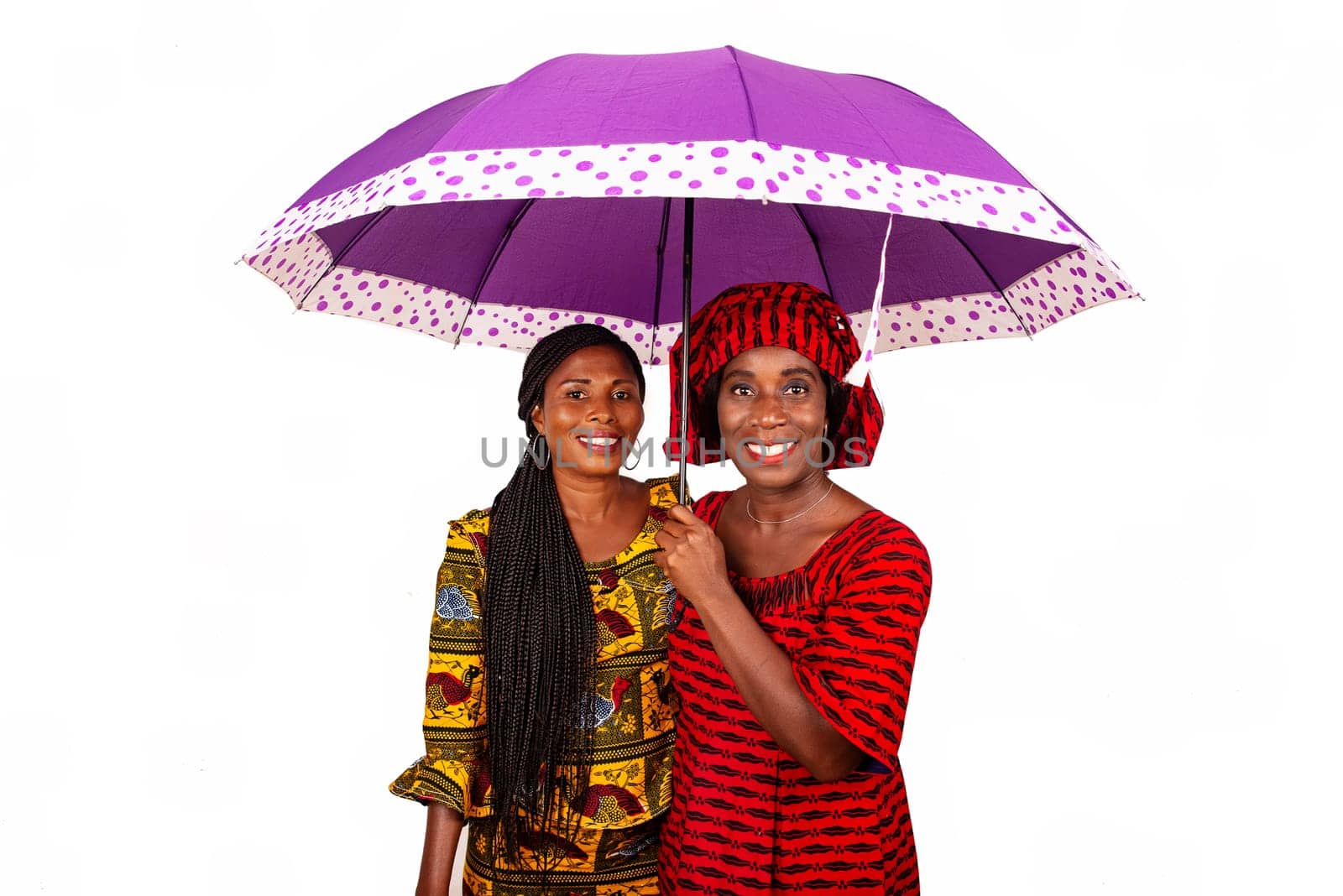 two beautiful business women standing together under a purple umbrella while being smiling