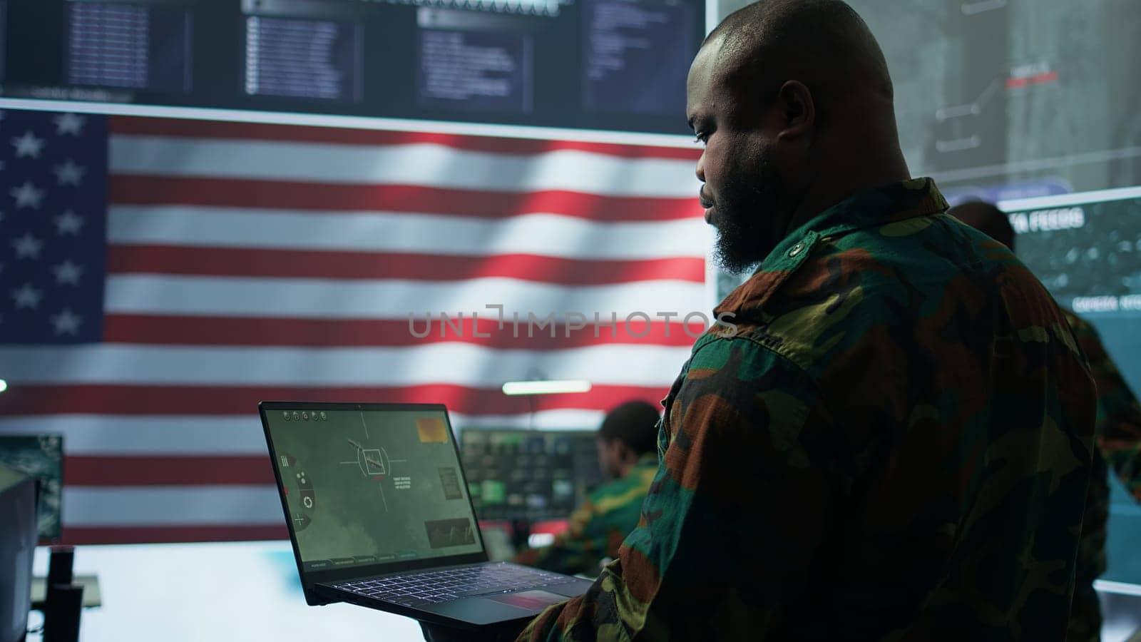 Intelligence officers in american military uniforms work on computers in a command post, managing surveillance and data analysis. Support global operations for the US government. Camera B.