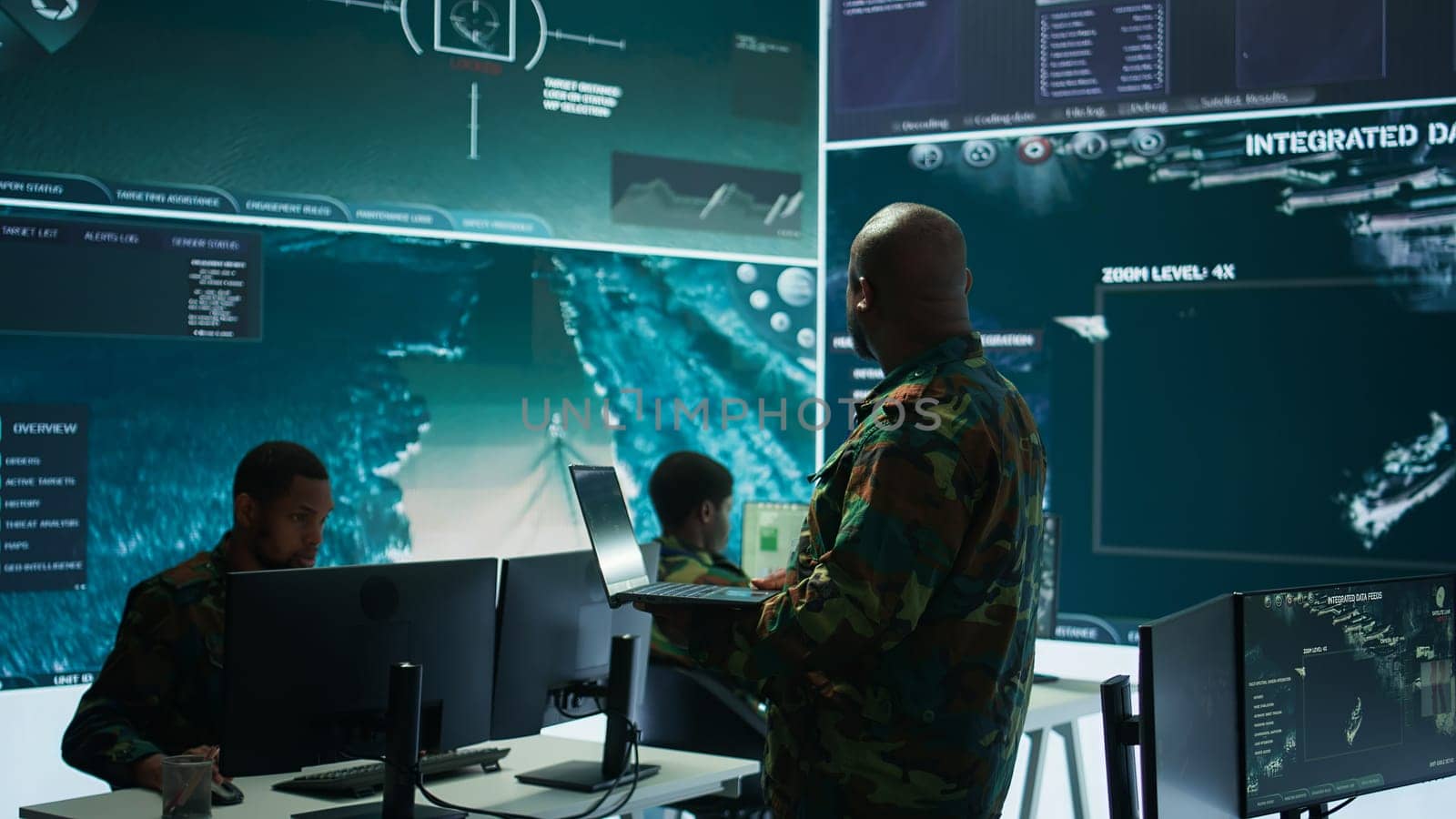 Cybersecurity team operates in an advanced military command center, surveillance systems and data protection. Army personnel work on national security operations using high tech gear. Camera B.