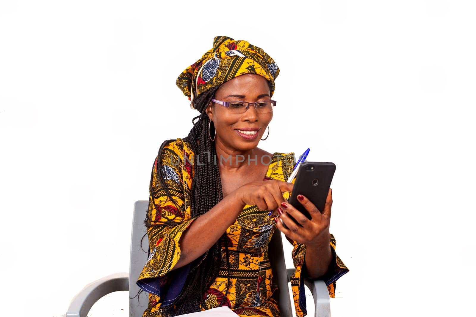 Portrait of happy adult businesswoman sitting pointing on smartphone screen outdoors writing in her notebook