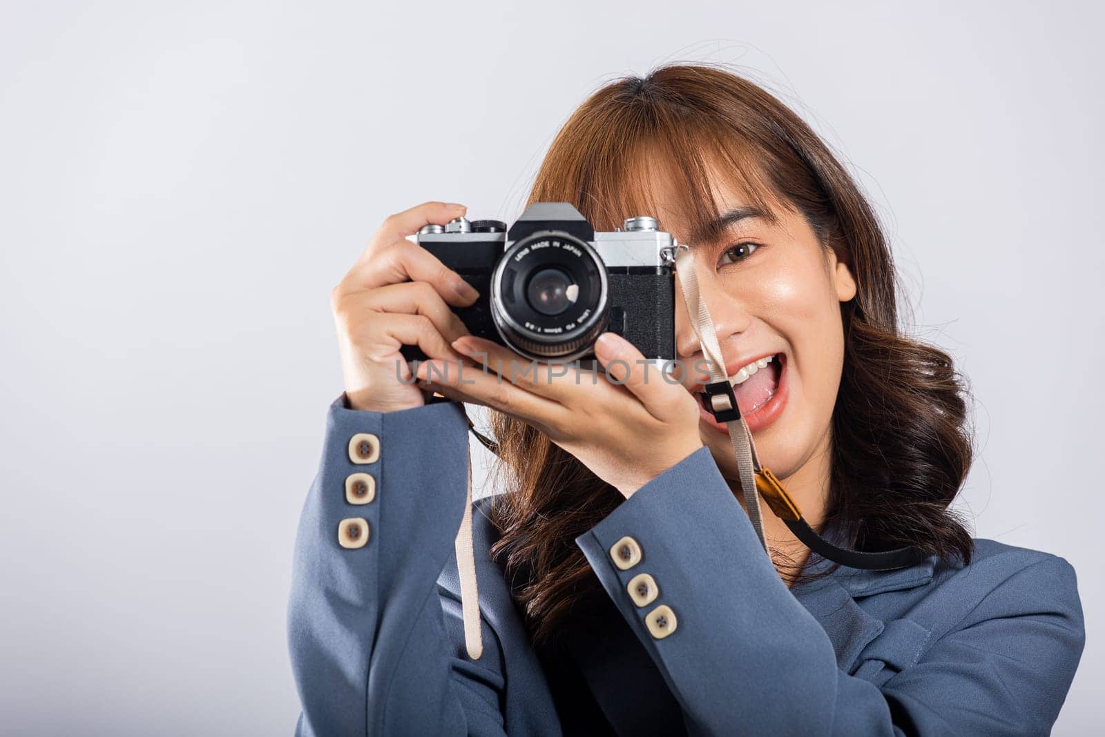 Attractive energetic happy Asian portrait beautiful business woman smiling photographer taking a picture and looking viewfinder on retro vintage photo camera ready to shoot isolated white background