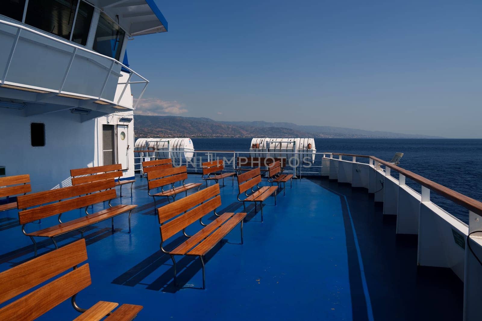 Sicily, Italy - 27.07.2024: Scenic ferry deck with empty benches overlooking the sea and distant horizon.