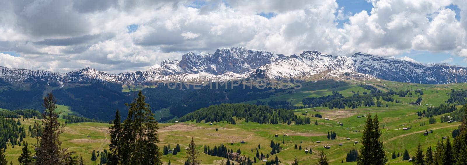 Majestic alpine landscape with snow capped mountains and verdant valleys near Valley of Funes at Dolomites, Italy.