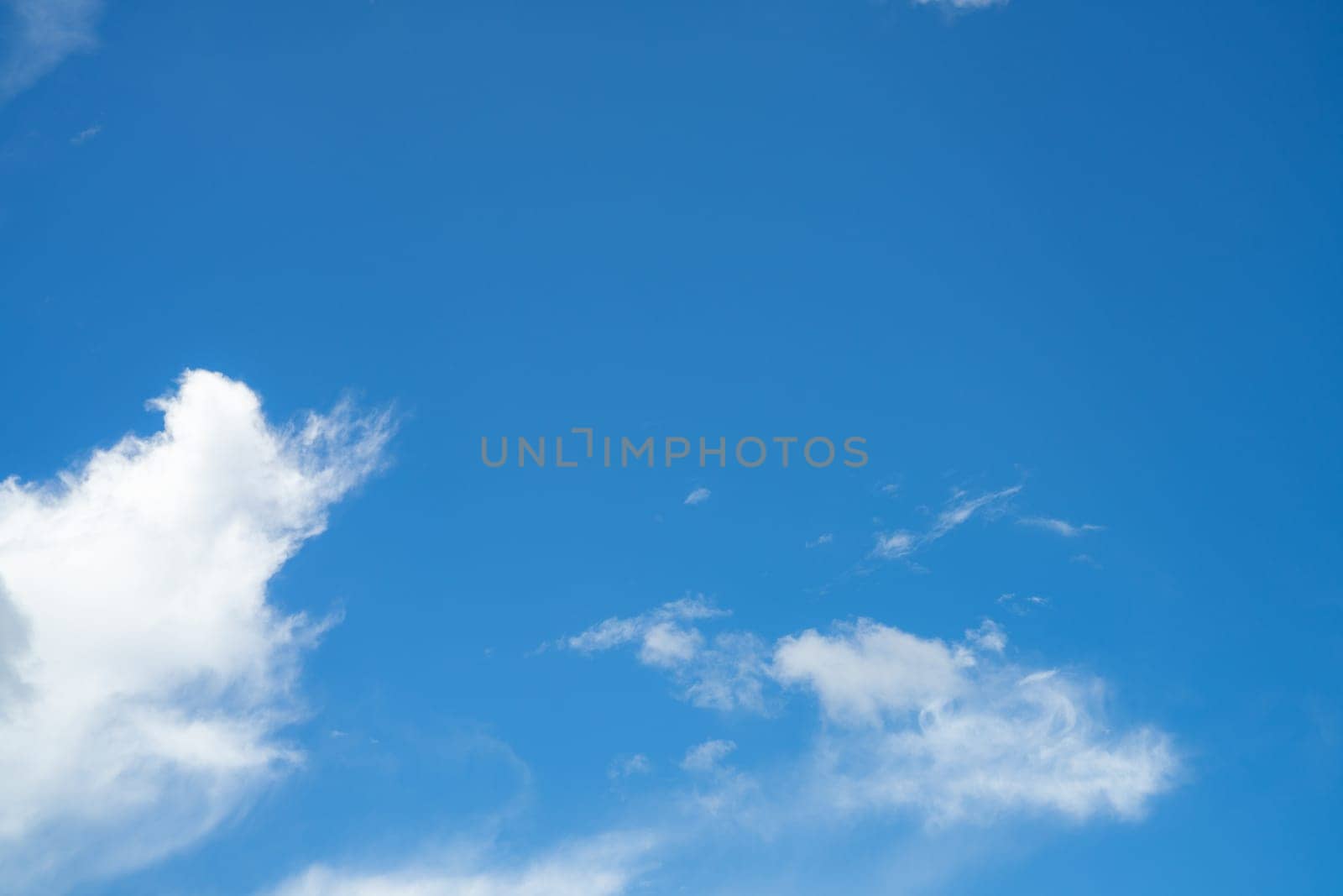 Blue sky with fluffy white cumulus clouds on bright sunny day, natural cloudscape background for environment and weather concepts. Summer day. Ozone awareness, clean air, environmental protection.