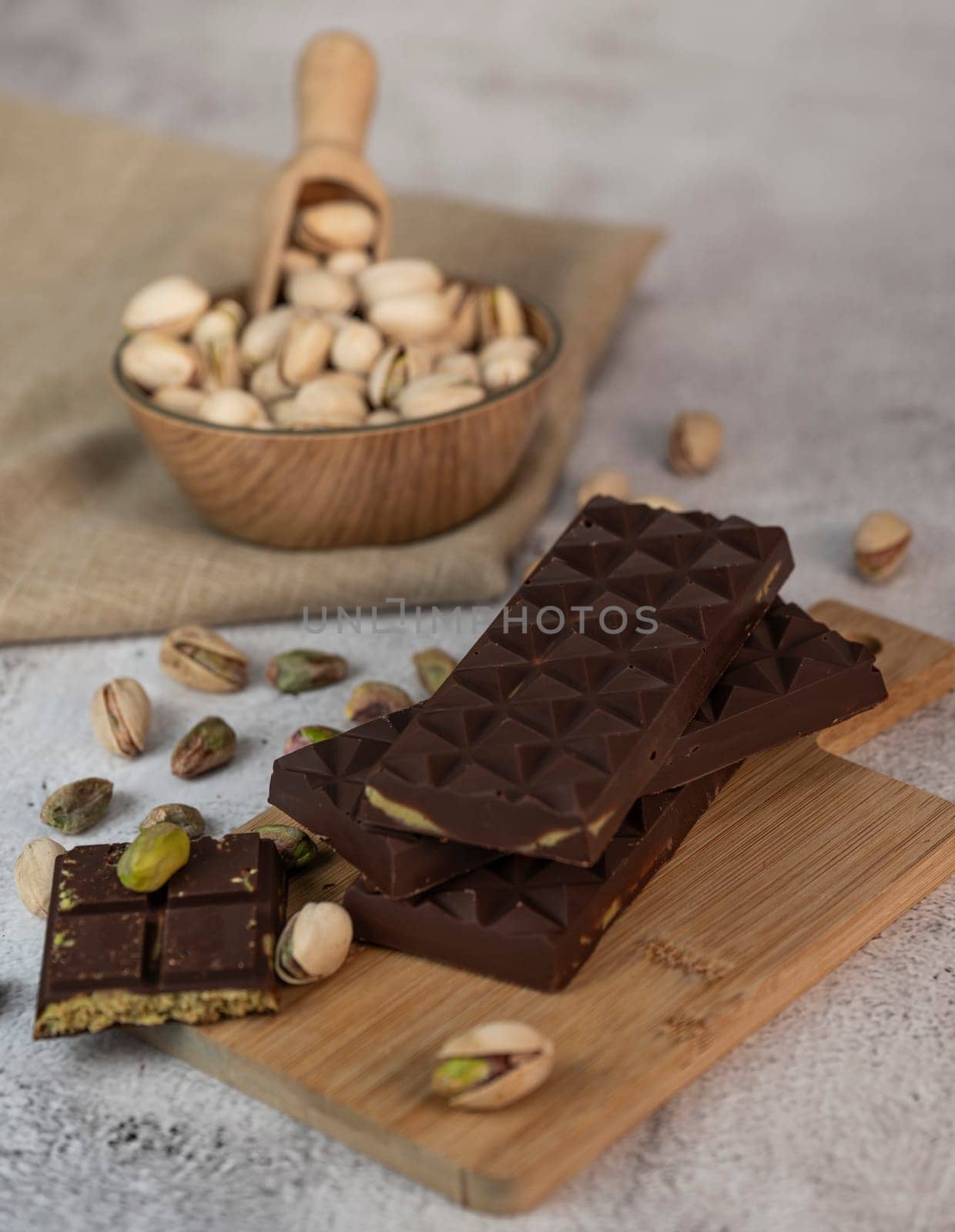 Gourmet chocolate mixed with crunchy kadaif pistachio pieces is beautifully presented on a wooden board, making a perfect treat in Dubai's culinary scene.