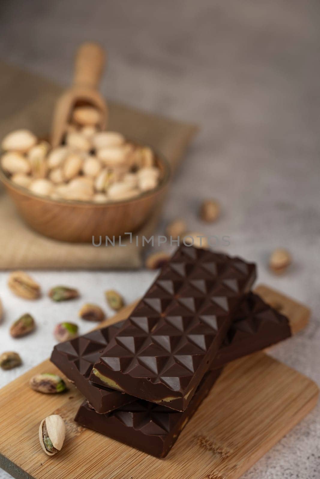 Gourmet chocolate mixed with crunchy kadaif pistachio pieces is beautifully presented on a wooden board, making a perfect treat in Dubai's culinary scene.