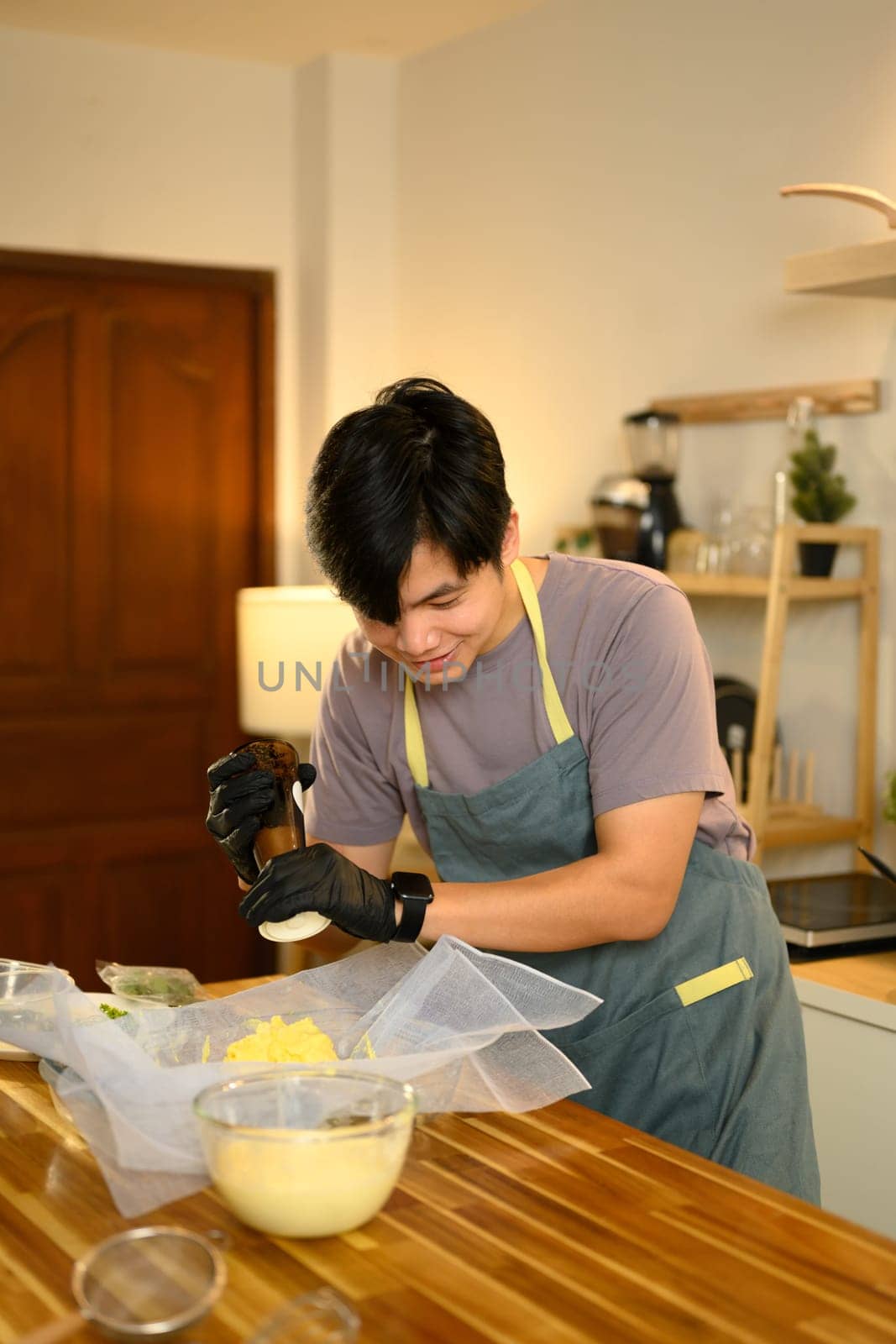 Smiling man seasoning churned butter with pepper, preparing to homemade compound butter.