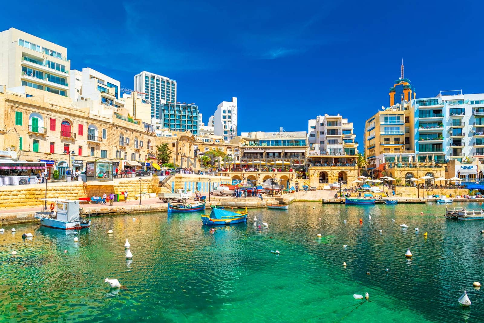 St Julian's Bay - April 12, Malta: Beautiful cityscape of the St Julian's Bay with boats lying on turquise water, hotel and residential buildings