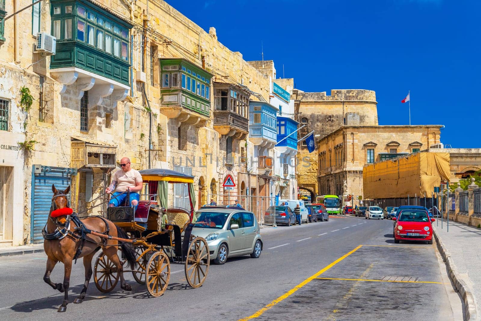 Valletta, Malta - April 2, 2025: A horse-drawn carriage moves among traffic along one of Valletta's streets