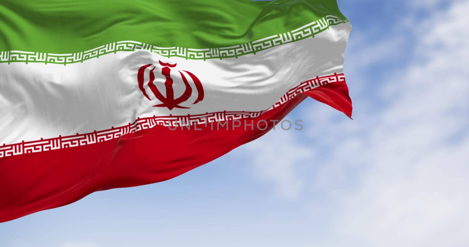 Close-up of Iranian flag with red, white, and green colors fluttering in the wind, featuring Kufic script and Islamic emblem. Symbol of national pride, unity, and identity in Western Asia.